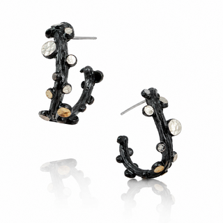 A pair of black branch-shaped hoop earrings adorned with clear faceted gemstones and small gold accents, displayed on a clean white background with a soft reflection below.