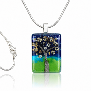 A rectangular fused glass pendant necklace featuring a stylized tree with metallic gold and silver circular branches over a blue-to-green gradient background, suspended from a silver snake chain on a white background.