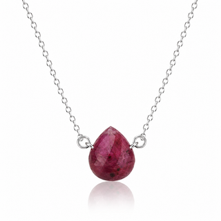 A silver chain necklace featuring a faceted teardrop-shaped ruby pendant with a polished silver bail and loop, displayed on a clean white background with a soft reflection below.