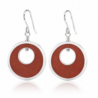 A pair of silver-tone dangle earrings with circular cutouts, featuring a textured reddish-brown center, shown on a white background with a soft reflection.